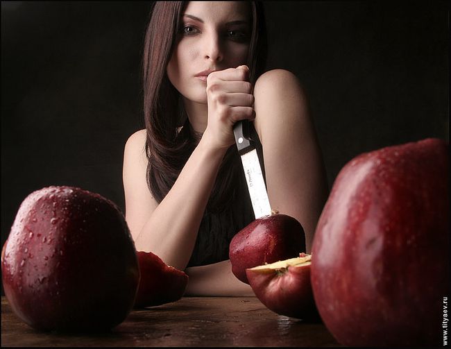 Apples A woman with a knife and a cut apple, with red delicious apples in the foreground